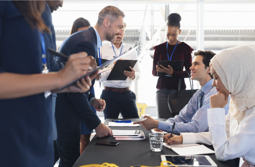Event check-in table with diverse staff and attendees using clipboards and digital devices—illustrating real-time tracking and onsite coordination from an event planning checklist for campus events.
